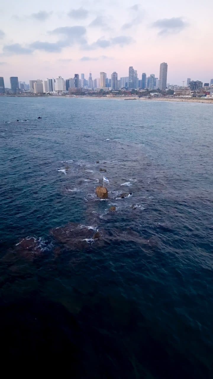 Rocks and sea off Jaffa with the Tel Aviv skyline at dusk